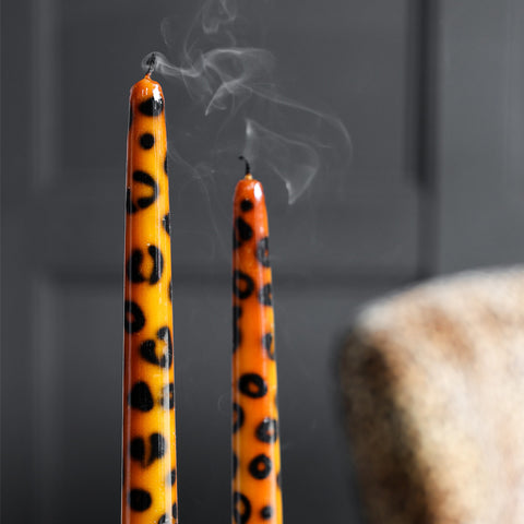 Lifestyle image of the Set of 2 Leopard Print Candles which have just been extinguished and have smoke rising from them.
