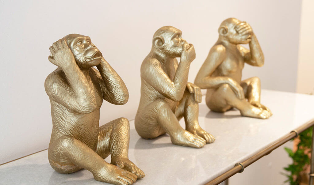 three wise monkey gold ornaments on sideboard