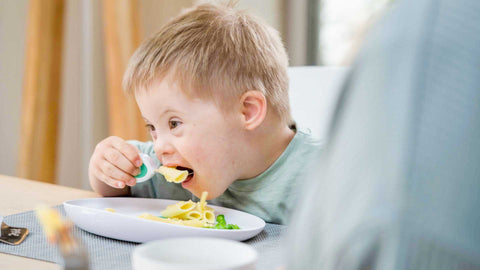 Little boy eating happily at the meal table