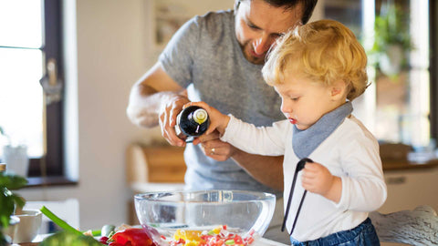 Dad and toddler son cooking together in a kitchen