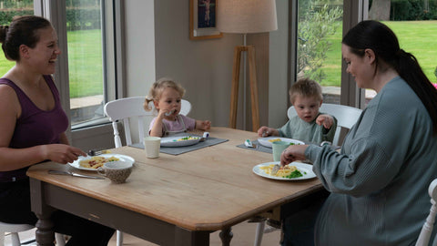 family sat around kitchen table enjoying a happy mealtime