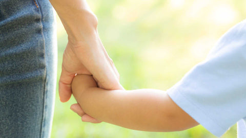 close up of parent hand holding a toddler hand as they stand outside