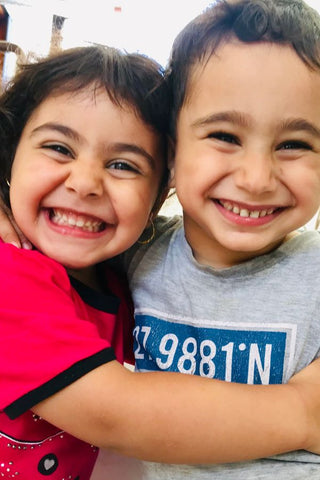 Two children smiling and hugging each other