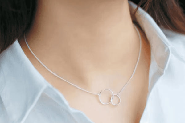 Woman wearing the Circle of Knowledge Necklace, featuring a minimalist design with interconnected circles on a silver chain