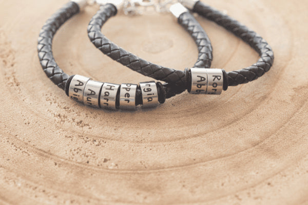 Personalized leather braided bracelet featuring silver beads with engraved names, perfect for gifting and stylish casual wear.