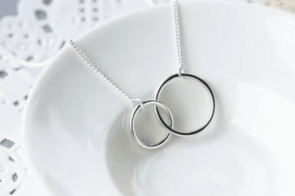 Elegant Circle of Knowledge Necklace with interlocking rings on a delicate chain displayed on a white plate.