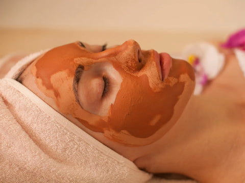 woman laying down with rose clay face mask on her face