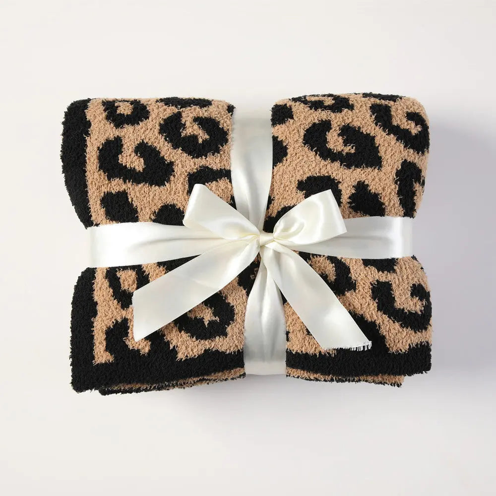 The Black Cuddley Leopard Decorative Throw Blanket folded up and a Ribbon tied around it.