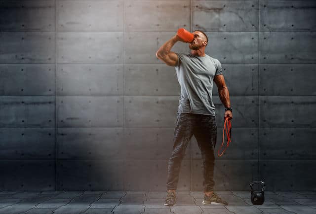 Muscular Man Drinks Protein drink After Workout.