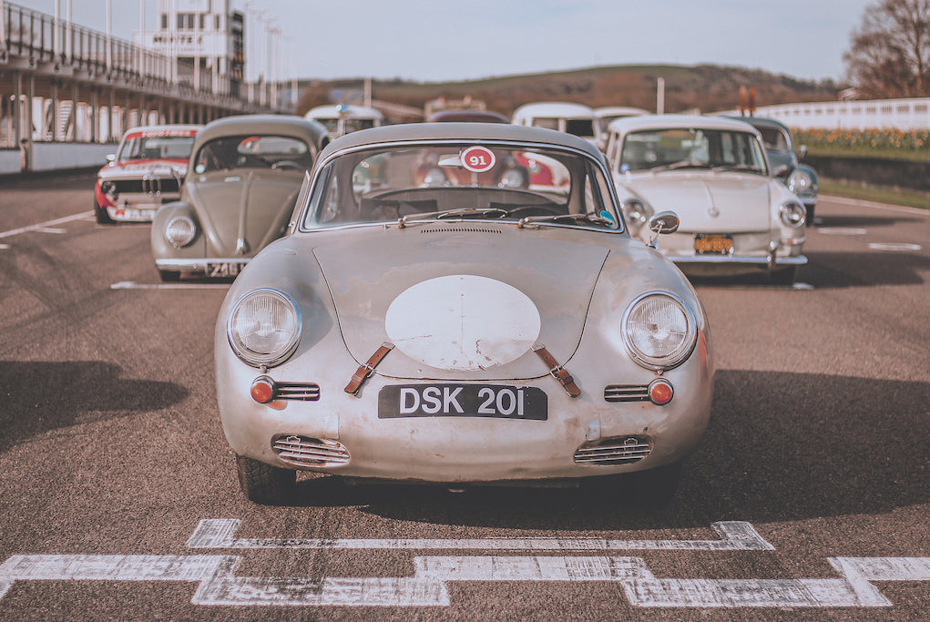 Cool Flo's silver Porsche on the starting grid at Goodwood race track with other classic cars in the background.