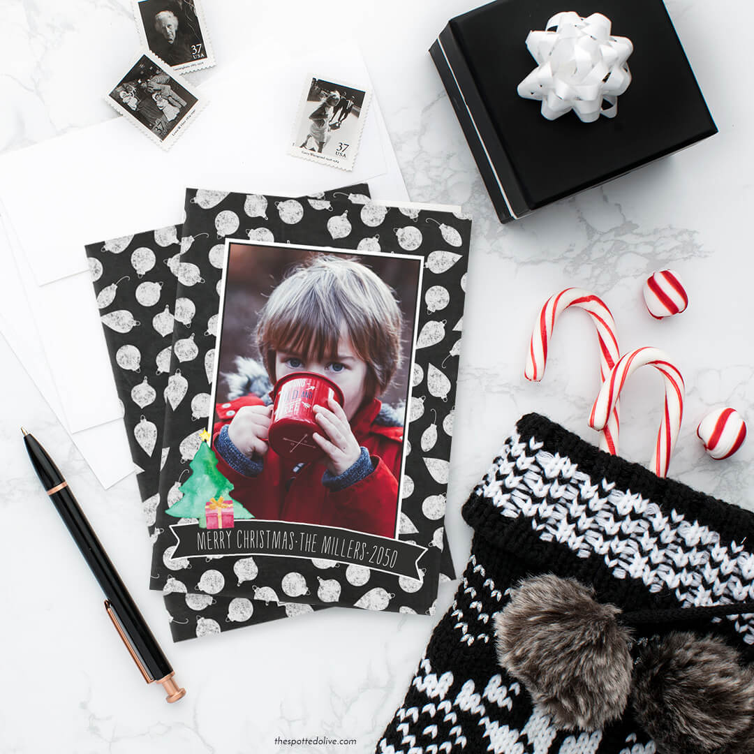 Personalized Holiday Photo Card on white marble surface with gifts, pen, christmas stocking, candy canes and postage stamps