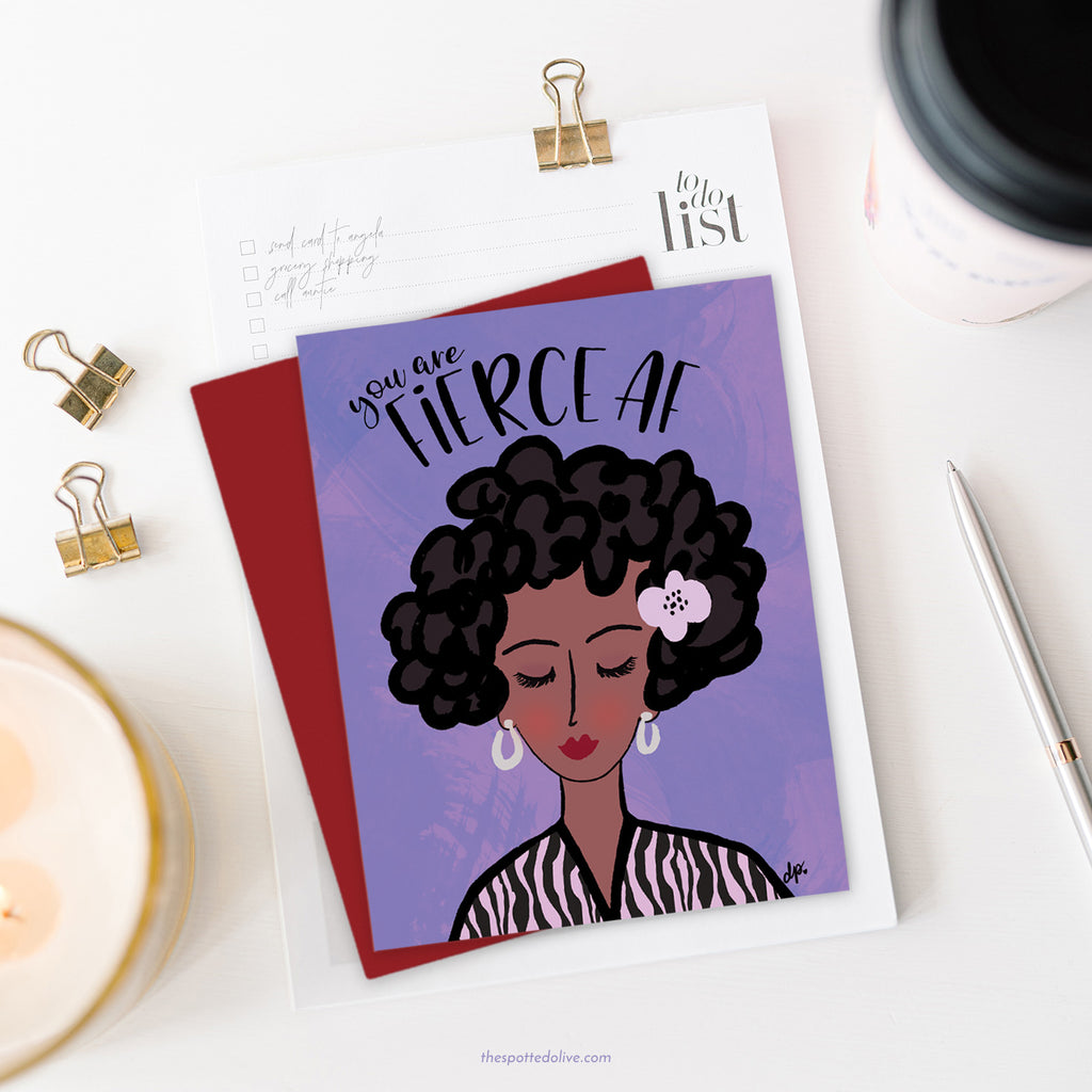 Fierce AF greeting card with red envelope on white desktop with candle, pen, clips and coffee