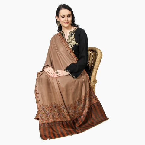 a Woman sitting on a chair wearing a brown color classic pashmina shawl with hand sozni embroidery