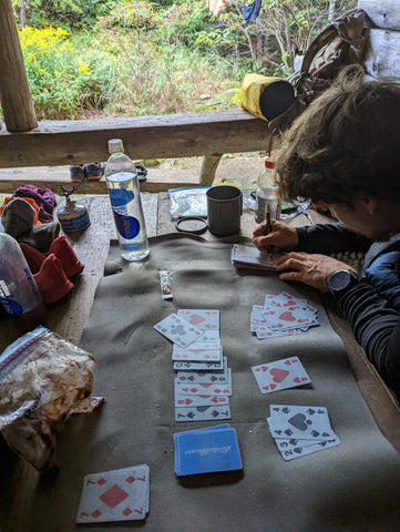 Hikers playing a card game in a dimly lit shelter