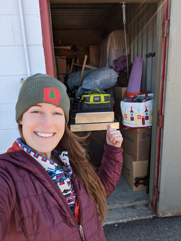 Woman standing in front of a full storage unit, pointing into the unit and smiling.
