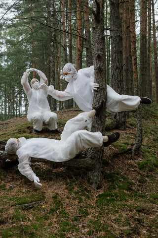 three people in hazmat suits doing funny poses in a forest