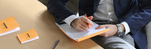 Rhodia orange staple bound pads being used at a desk