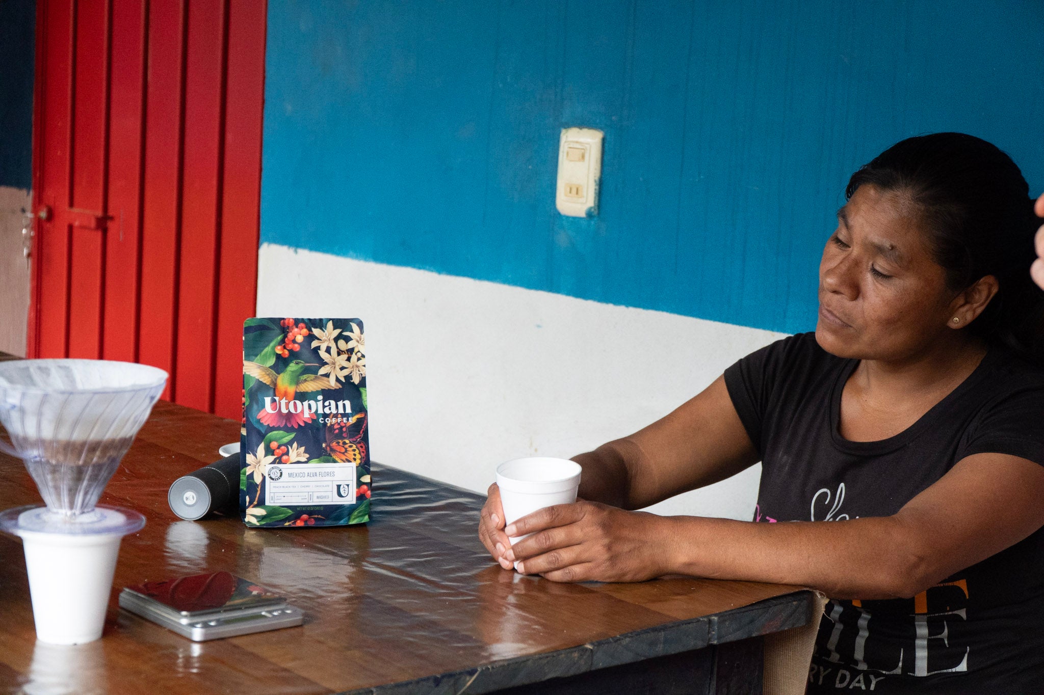 coffee farmer looking at coffee bag with her name on it next to a V60 dripper