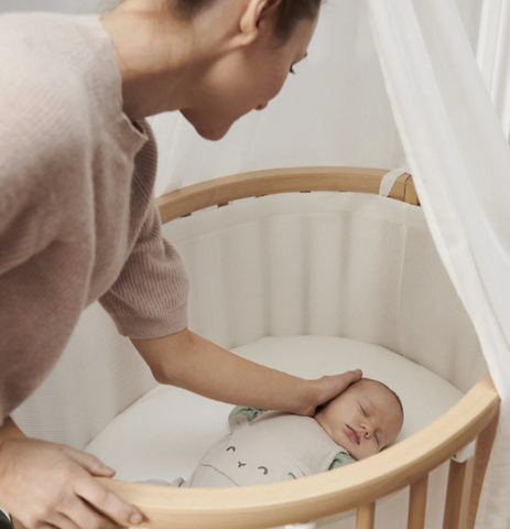 Parent looking at baby in Stokke Sleepi Mini bassinet