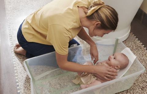 Woman bathing baby with tub perfect for first trip with baby