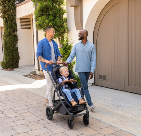 two dads with child in uppababy cruz stroller