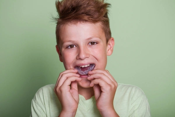 A child putting on a night guard to protect his teeth.