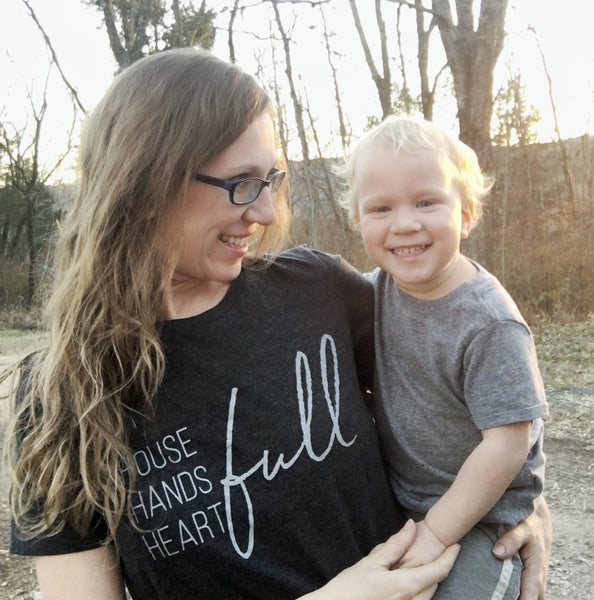 Julie Kreke wearing house is full graphic tee carrying baby boy