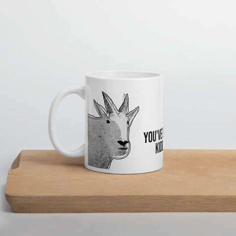 A glossy funny mountain goat mug sitting on a wooden shelf