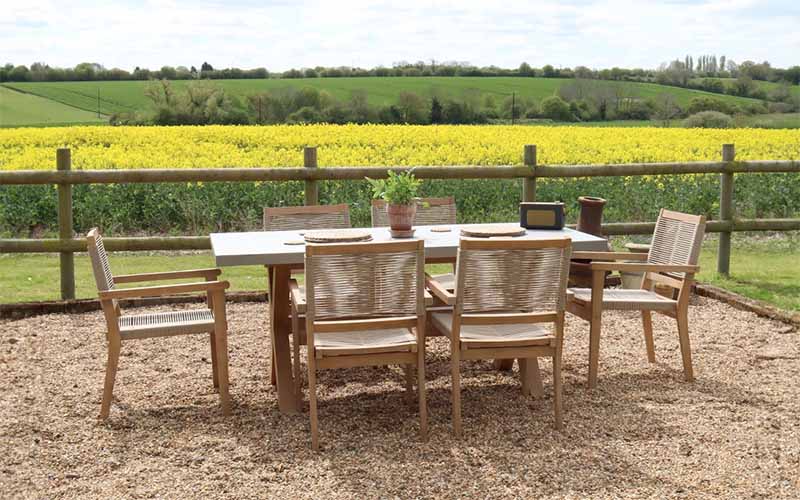 Full view of the Luna 6 Seater Rectangular Concrete Dining Set, featuring a sleek concrete table and stylish rope stacking chairs, set against a scenic outdoor backdrop.