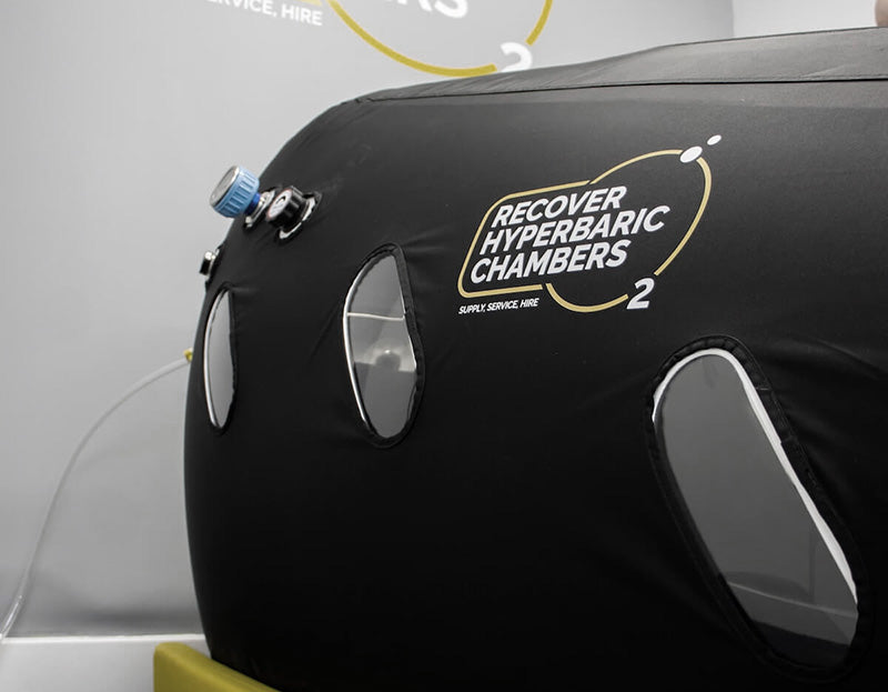 Close-up of Recover hyperbaric chamber showing viewing windows and logo.