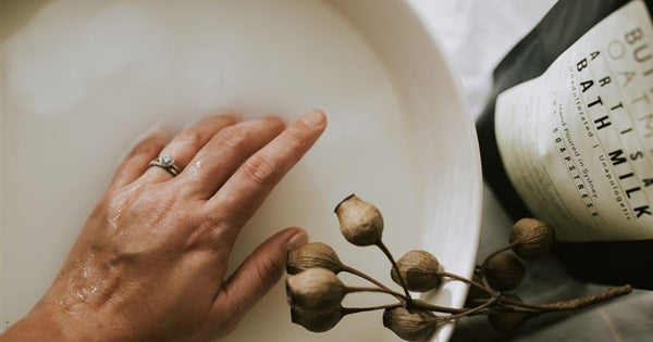 A woman is emerging her hand into a hydrating and luxurious milk bath