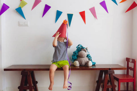 a kid at his birthday party with a plushie next to him