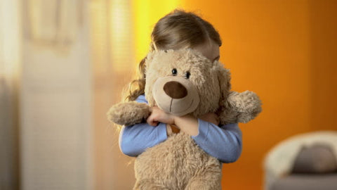 child hugging teddy bear