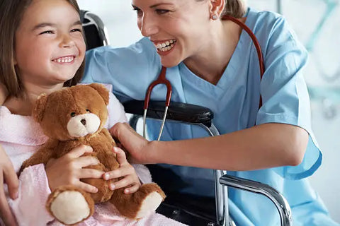 nurse with child patient and the child is holding a teddy bear