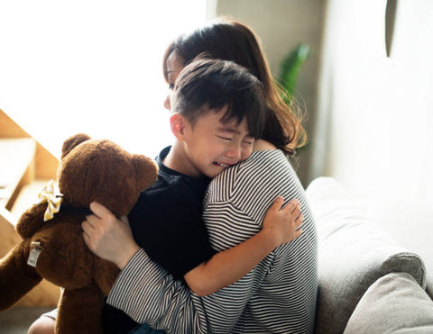 a crying kid hugging his mother