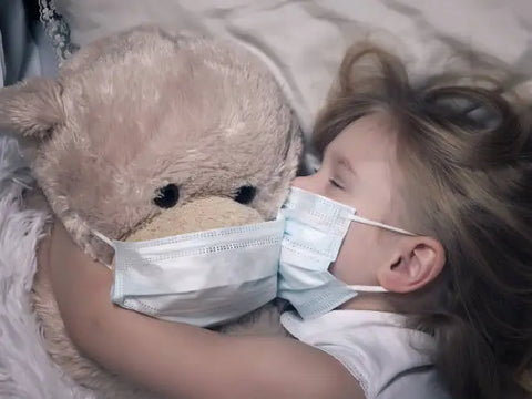 kid hugging a plushie, both have a mask on