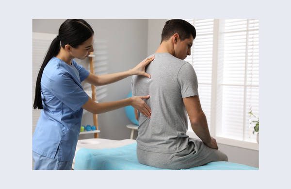 doctor feeling the spine of a patient sitting upright on an exam table