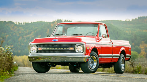Image is of a 1970 Chevy Squarebody truck, red, parked on a hilltop overlooking a misty valley