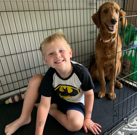 Maisy the dog in the kennel with her human brother.