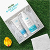 Bath & body care kit with products in box, rubber duck, on grass with towel.