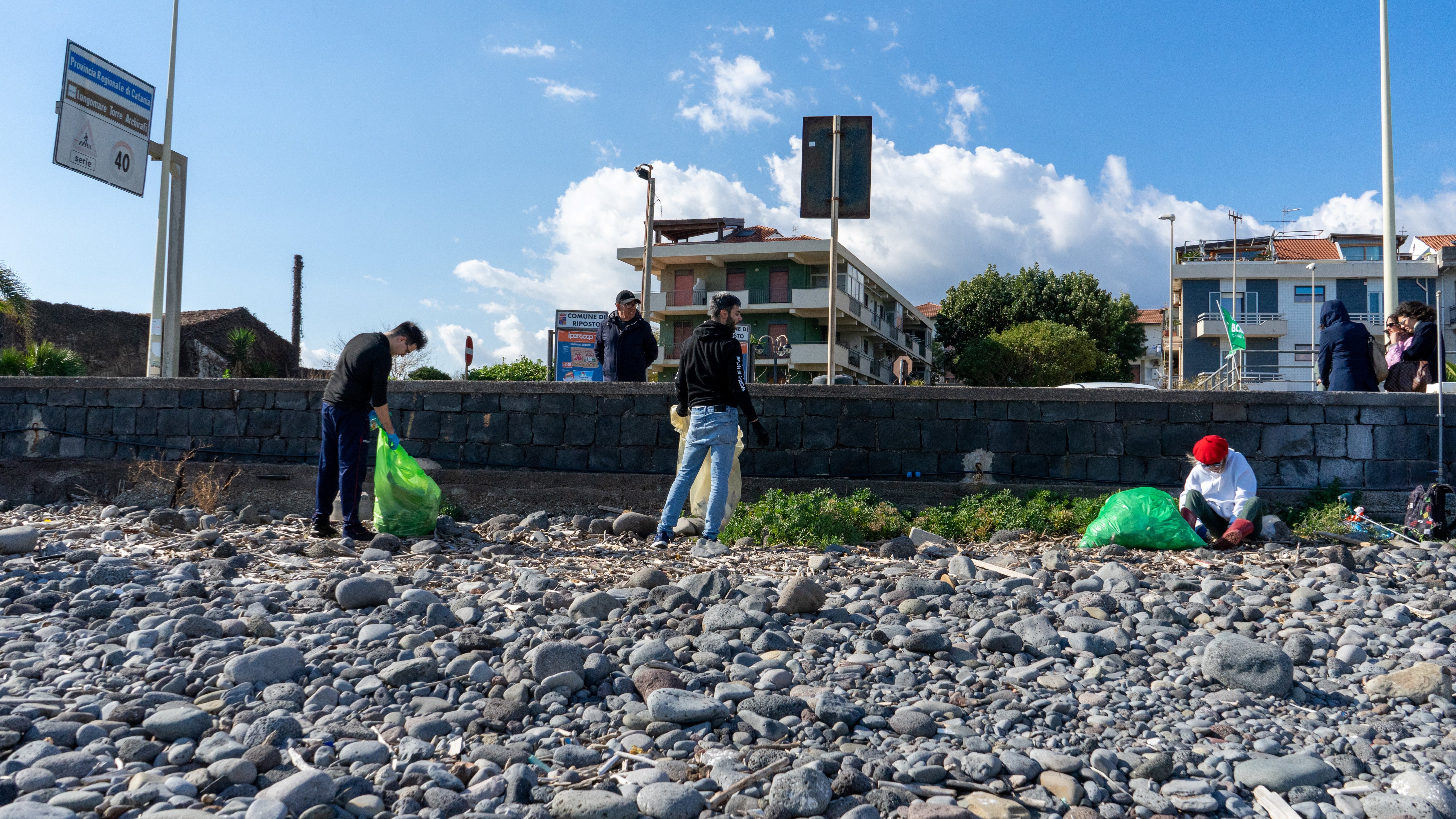 Volontari mentre ripuliscono dai rifiuti la spiaggia di Riposto in provincia di Catania
