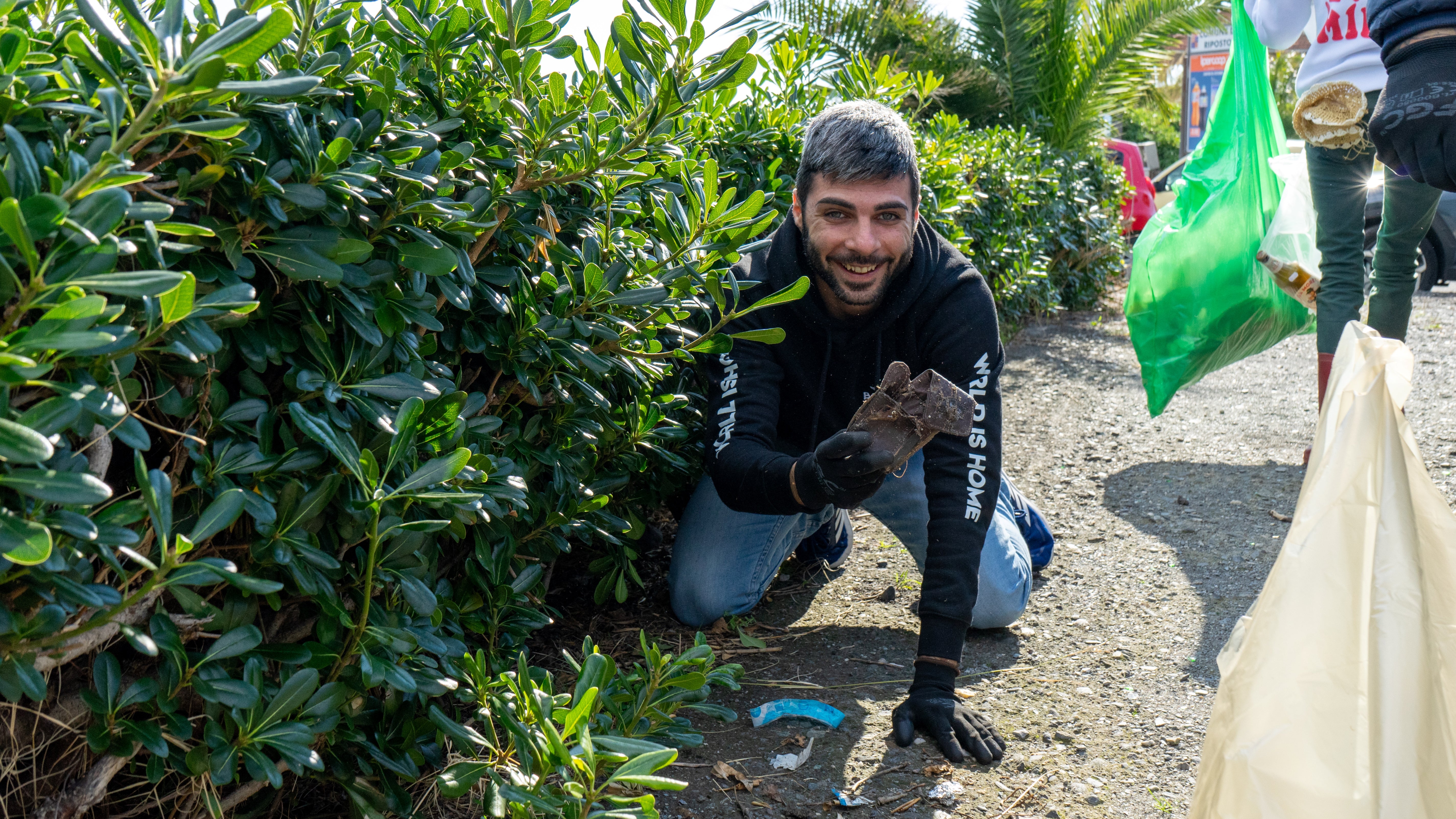 Volontario mentre raccoglie rifiuti in una siepe a Riposto - Cleaning With Bongae