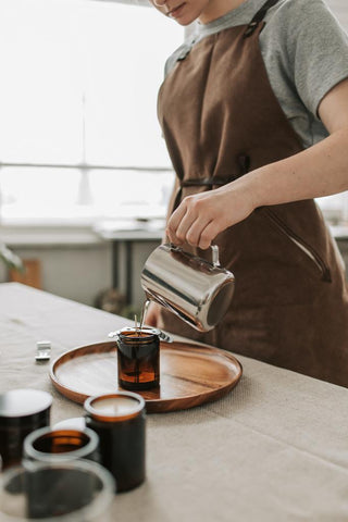 Woman pouring DIY candle made with coffee grounds