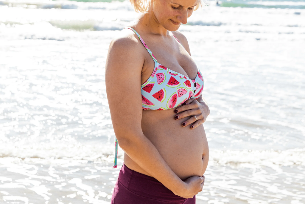 Těhotná žena na pláži v bikinách