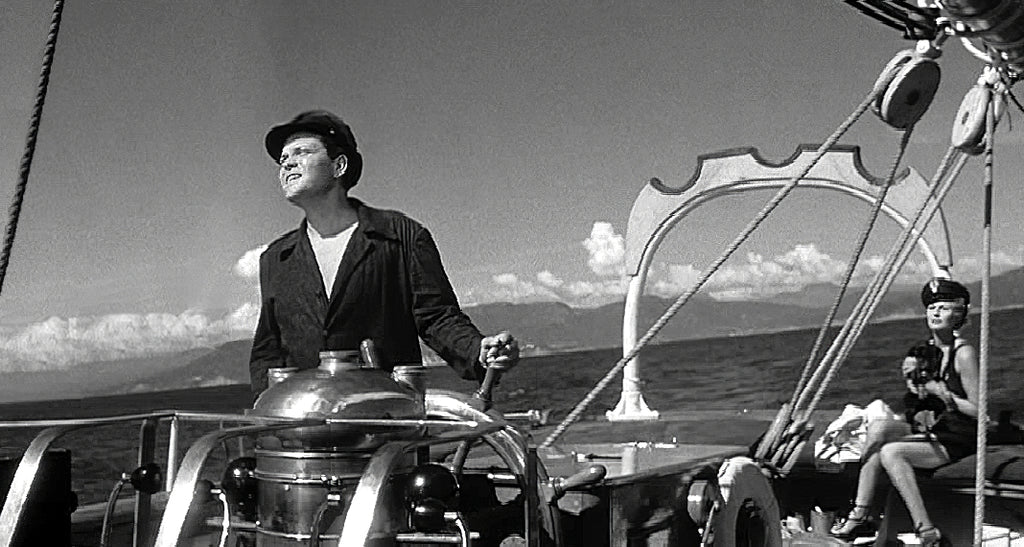 Fotograma de «La dama de Shanghai» con Orson Welles y Rita Hayworth sosteiendo en sus brazoa a Aerno, el querido schnauzer de Errol Flynn, quien también tuvo un cameo en la película.