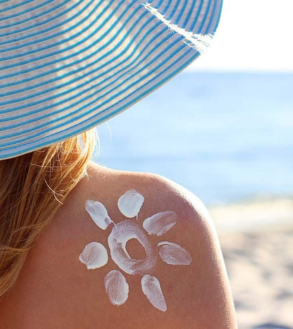 woman with hat and sunscreen - skincare essentials