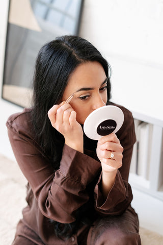 Girl tweezing her eyebrows using ArteStile Point Tip Tweezers in the colour sand.