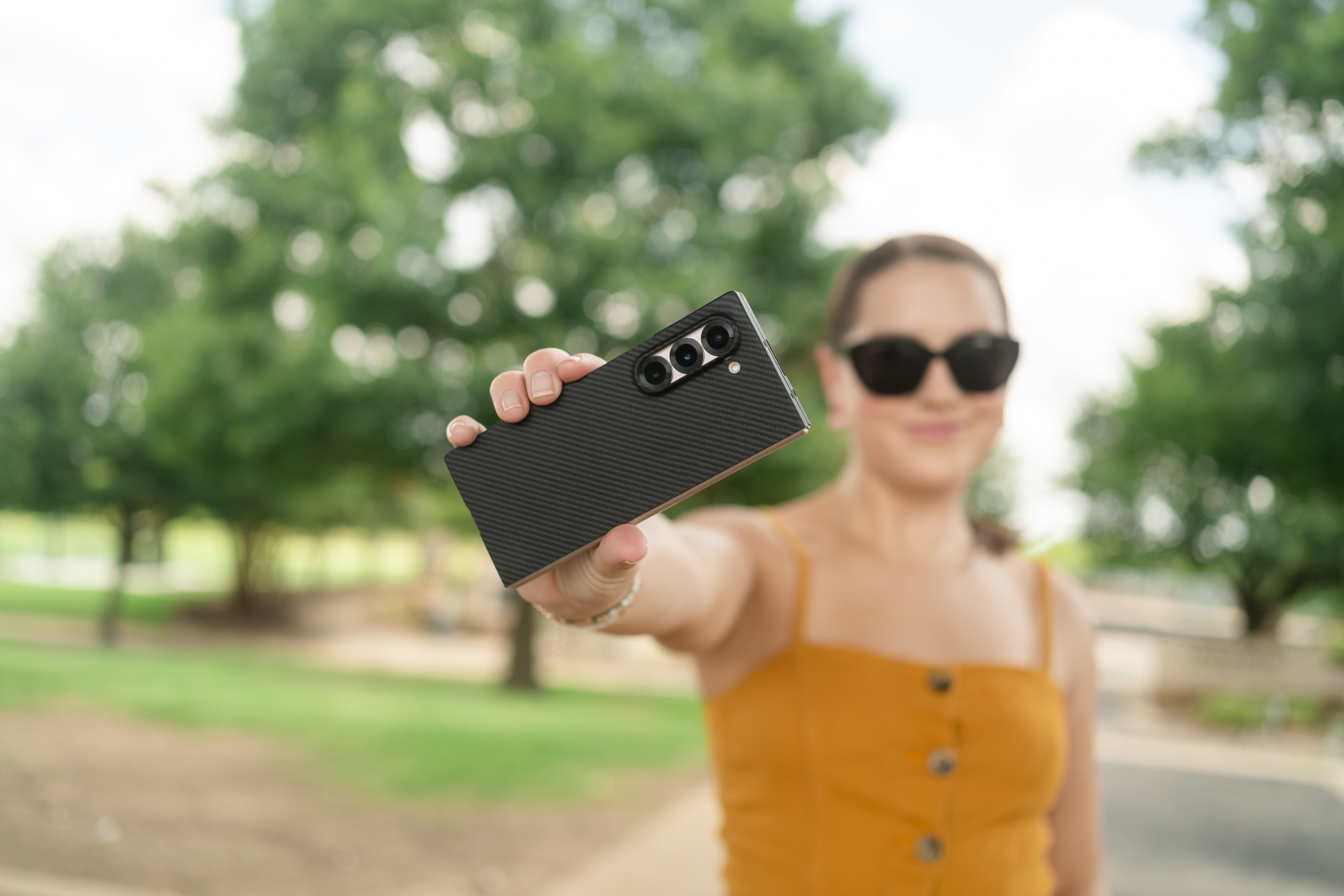 a young lady showing the galaxy z fold 6 carbon fiber case with the phone