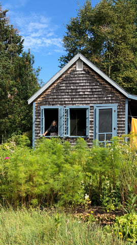 Barbara Beebe waves from the jewelry studio slash wood shed