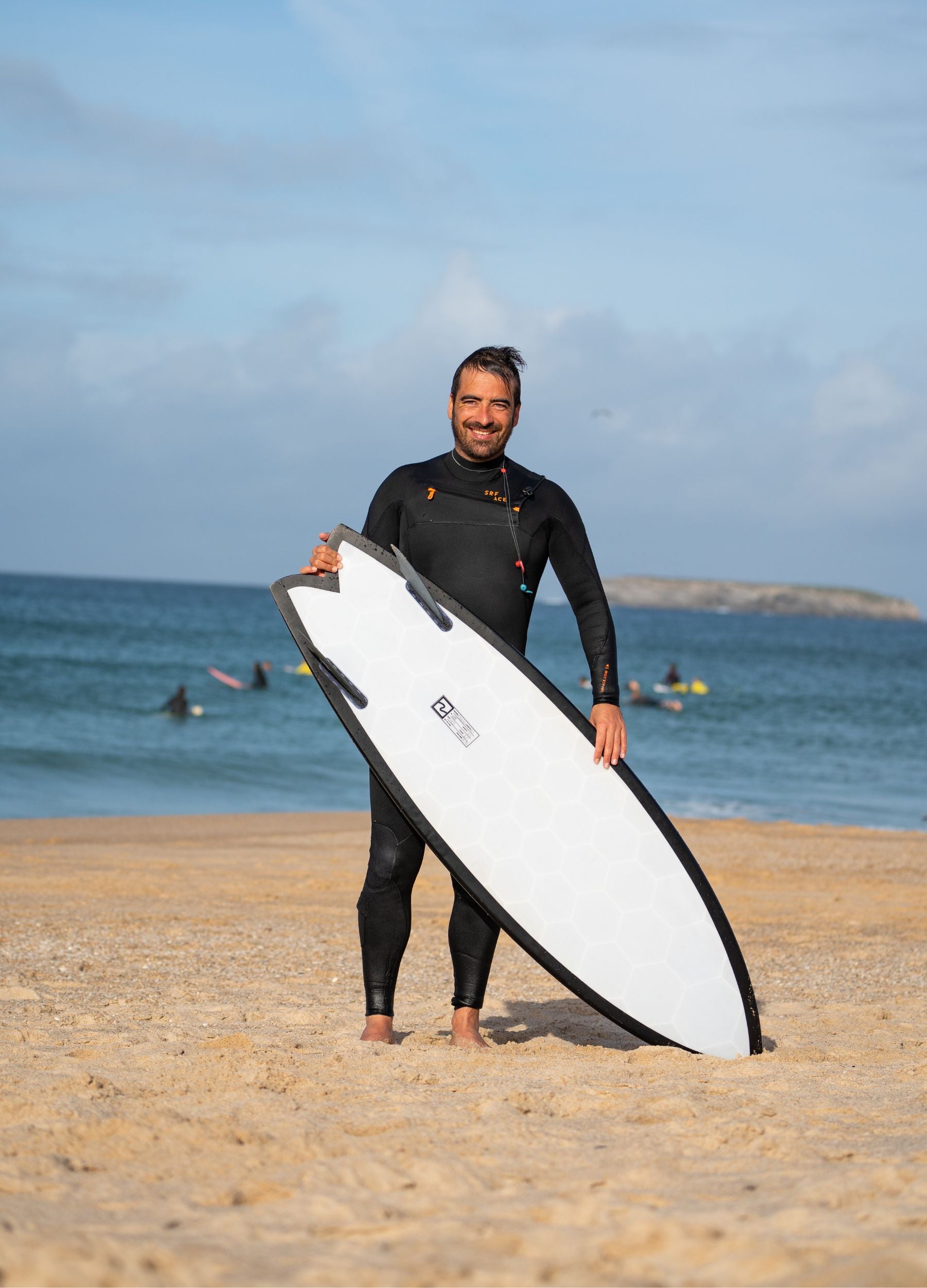 Erik walking along the beach carrying his Wyve surfboard after finishing a surf session